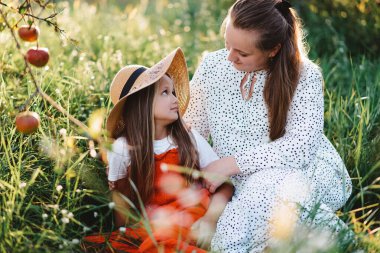Anne ve kızı yüzlerinde bir gülümsemeyle birbirlerine bakıyorlar.