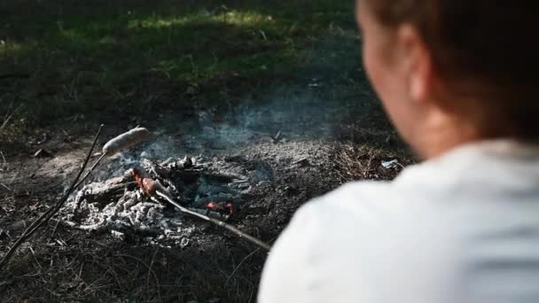 Μια Γυναίκα Μαγειρεύει Ένα Λουκάνικο Μια Φωτιά Στο Δάσος — Αρχείο Βίντεο