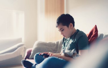 Eğitim konsepti, okul çocuğunun internetten cep telefonu hazırlama hikayesi, çocuğun evde online öğrenim görmesi, çocuğun cep telefonu oyunu oynaması ya da arkadaşlarıyla sohbet etmesi,