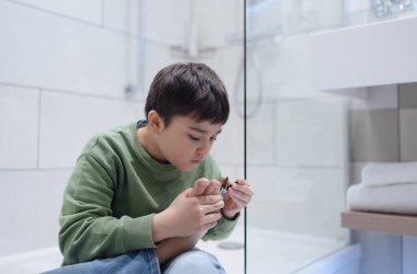 Çocuğun banyoda tırnaklarını kestiği portre, tırnak makasıyla tırnak kesen çocuk, çocuk sağlığı ve hijyen bakımı, pedikür konsepti.