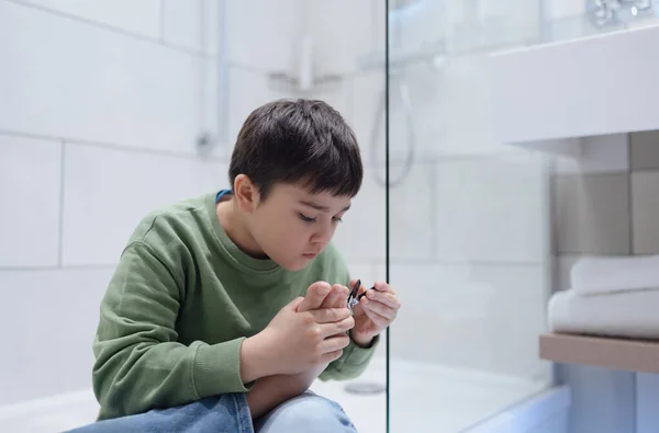 ポートレートキッドバスルームで爪をクリッピング 子供の男の子爪クリップでつま先の爪を切断 子供の健康と衛生ケア ペディキュアコンセプト — ストック写真