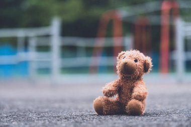 Kayıp oyuncak ayı, kasvetli bir günde oyun parkında oturuyor, yalnız ve üzgün kahverengi ayı, parkta yalnız oturuyor, Kayıp oyuncak ya da yalnızlık konsepti, uluslararası kayıp çocuklar günü
