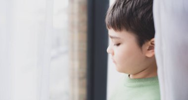 Portre Ufaklığı, üzgün yüzlü okul çocuğu, pencerenin kenarındaki perdelerin arkasına bakan genç çocuk, Duygusal Düşünen Yüz 'ü kapatın ve Çocuk' un derin düşüncelerine bakın.