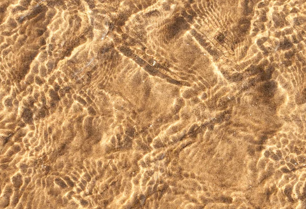 透明な海の波の反射を持つ砂質のテクスチャパターン アブストラクト波状の茶色の砂の波紋の上の水面に太陽光 夏のビーチの位置のための海の底の背景バナー — ストック写真