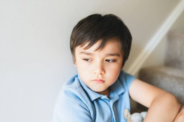 Düşüncelere dalmış portre çocuğu merdivenlerde oturan yalnız çocuk düşünceli yüz, çocukluk ve aile kavramı seçici odaklı duygusal çocuk portresi.