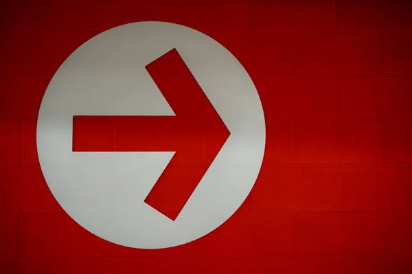 Arrow sign in white circle on red brick wall background, Directional Arrow  pointing to right side