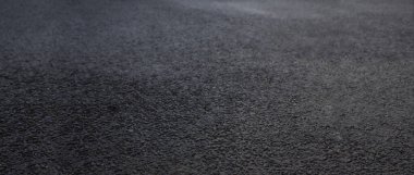 Koyu küçük kaya taşlarının karışık kısmından kaba doku yüzeyine sahip asfalt yolun arka planı 