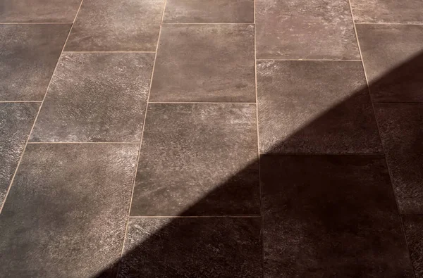 Stone floor of natural slate tile paving with sunlight shadow overlay