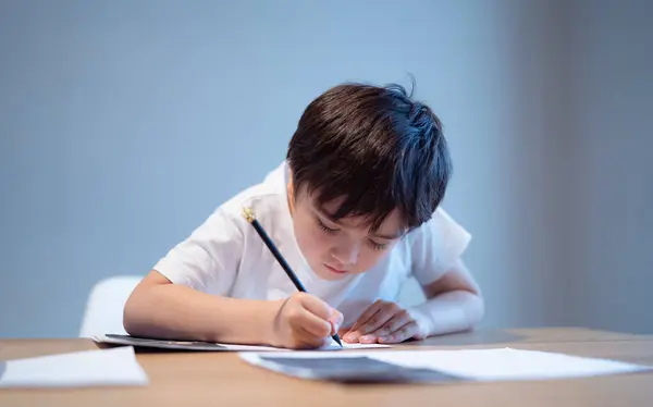Хлопчик Сидить Столі Робить Домашнє Завдання Тримає Чорну Ручку Білому — стокове фото