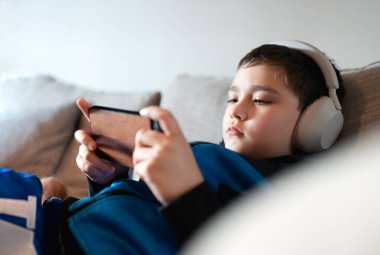 Okula dönüyorum. Akıllı telefonla ödev yapan bir çocuk düşünüyorum. Evde eğitim konsepti, kulaklıkla portre öğrenci İngilizce öğreniyor. Bağımlı Çocuk oyunu ya da müzik dinlemek