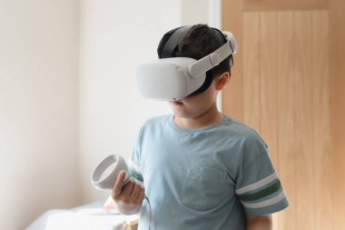 Kid boy playing with virtual reality goggles or VR headset, Child having fun indoors activity with family at home,Concept Video Gaming with learning modern technology glasses for School Children clipart