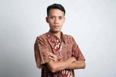 Batik tişört giyen mutlu Asyalı bir adamın portresi beyaz arka planla izole edilmiş bir şekilde gülümsüyor.