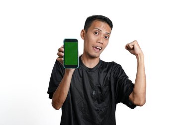 Asian man wearing black training t-shirt, With a happy excited gesture while looking at the smartphone screen. Isolated by white background