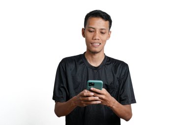 Asian man wearing black training t-shirt, With a happy excited gesture while looking at the smartphone screen. Isolated by white background