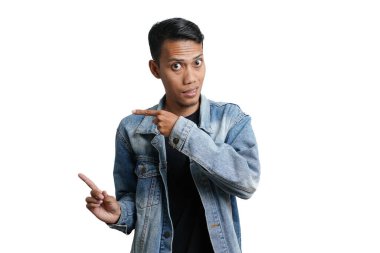 asian man wearing blue jean jacket pointing beside copy space for advertisement, isolated on white background