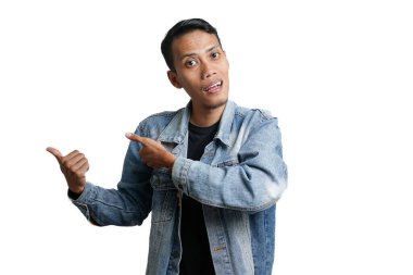 asian man wearing blue jean jacket pointing beside copy space for advertisement, isolated on white background
