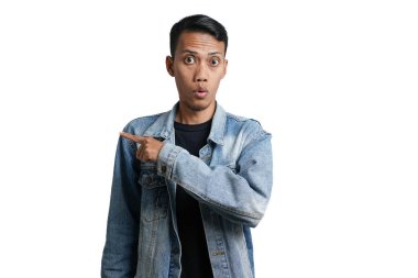 asian man wearing blue jean jacket pointing beside copy space for advertisement, isolated on white background