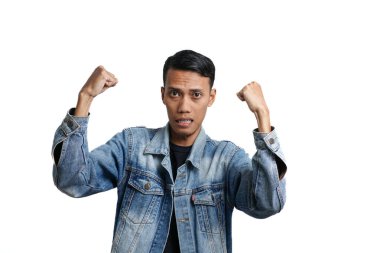 Asian man wearing blue jean jacket doing victory gesture, hands clasped. Isolated by white background