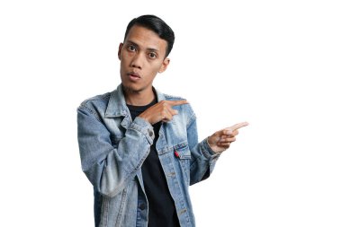 asian man wearing blue jean jacket pointing beside copy space for advertisement, isolated on white background