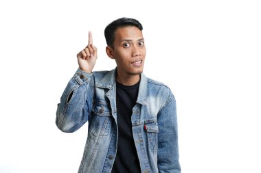 asian man wearing blue jean jacket pointing up copy space for advertisement, isolated on white background