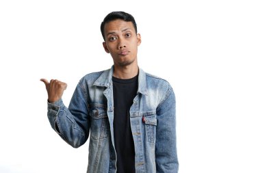 asian man wearing blue jean jacket pointing beside copy space for advertisement, isolated on white background