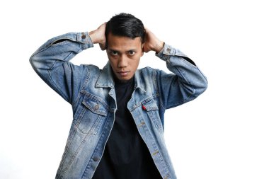Asian man wearing a blue jean jacket poses cool, quirky like a model. Isolated by white background