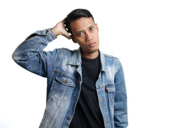 Asian man wearing a blue jean jacket poses cool, quirky like a model. Isolated by white background