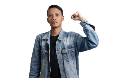 Asian man wearing blue jean jacket doing victory gesture, hands clasped. Isolated by white background