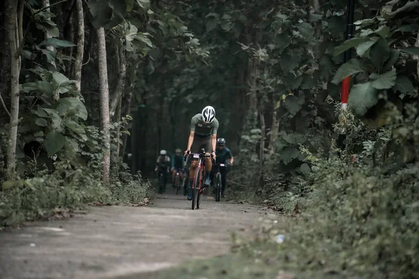 헬멧을 사이클 리스트는 자전거를 시골길을 갑니다 언덕을 오르기 자전거를 이용하는 로열티 프리 스톡 사진