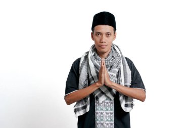 Asian muslim man wearing turban, muslim dress and cap, greeting with big smile on his face. Isolated on white background. Greetings ramadahan or Eid al-Fitr