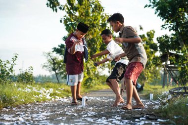 Yogyakarta, Endonezya - 16 Nisan 2023: Bazı çocuklar sabah namazından eve dönerken, Ramazan ayı boyunca köyün sokaklarında havai fişek atarken hala Müslüman gibi görünüyorlar