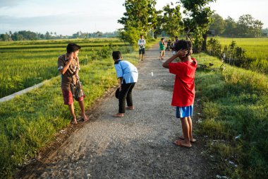 Yogyakarta, Endonezya - 16 Nisan 2023: Bazı çocuklar sabah namazından eve dönerken, Ramazan ayı boyunca köyün sokaklarında havai fişek atarken hala Müslüman gibi görünüyorlar
