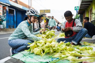 Kotagede pazar yolu etrafındaki perakendecilerden ketupat yuvaları alan alıcılar, geleneksel Kurban Bayramı yemeği hazırlıyorlar. : Yogyakarta, Endonezya - 20 Nisan 2023