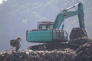 Piyungan 'ın son atık sahasında kazıcı taşıyan leş yiyiciler tarafından görülen büyük çöp yığınları birikti. Yogyakarta 'da atık yönetimi acil durumu.