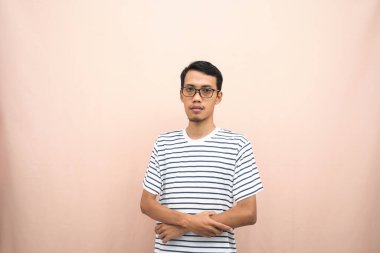 Gözlüklü, sıradan çizgili gömlek giyen, kollarını kavuşturmuş, gülümseyen ve ciddi bir şekilde duran Asyalı bir adam..