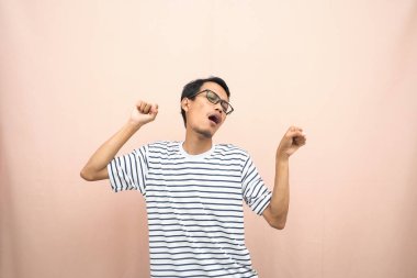 Gözlüklü, sıradan çizgili tişört giyen Asyalı bir adam. Mutlu bir jest ve sürpriz. Ayrı bej arkaplan.