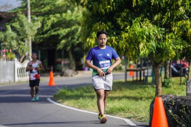 Jogja Maratonu 42K 'nın katılımcıları veya koşucuları, Prambanan tapınak köyünün etrafından güzel bir yoldan geçiyorlar. : Yogyakarta, Endonezya - 18 Haziran 2023