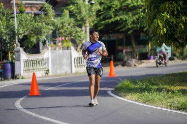 Jogja Maratonu 42K 'nın katılımcıları veya koşucuları, Prambanan tapınak köyünün etrafından güzel bir yoldan geçiyorlar. : Yogyakarta, Endonezya - 18 Haziran 2023