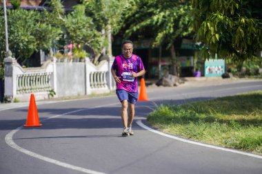 Jogja Maratonu 42K 'nın katılımcıları veya koşucuları, Prambanan tapınak köyünün etrafından güzel bir yoldan geçiyorlar. : Yogyakarta, Endonezya - 18 Haziran 2023