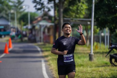 Jogja Maratonu 42K 'nın katılımcıları veya koşucuları, Prambanan tapınak köyünün etrafından güzel bir yoldan geçiyorlar. : Yogyakarta, Endonezya - 18 Haziran 2023