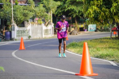 Jogja Maratonu 42K 'nın katılımcıları veya koşucuları, Prambanan tapınak köyünün etrafından güzel bir yoldan geçiyorlar. : Yogyakarta, Endonezya - 18 Haziran 2023