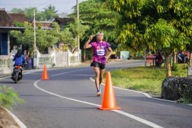 Jogja Maratonu 42K 'nın katılımcıları veya koşucuları, Prambanan tapınak köyünün etrafından güzel bir yoldan geçiyorlar. : Yogyakarta, Endonezya - 18 Haziran 2023