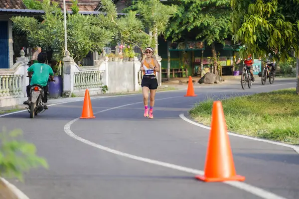 Jogja Maratonu 42K 'nın katılımcıları veya koşucuları, Prambanan tapınak köyünün etrafından güzel bir yoldan geçiyorlar. : Yogyakarta, Endonezya - 18 Haziran 2023