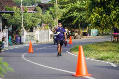 Jogja Maratonu 42K 'nın katılımcıları veya koşucuları, Prambanan tapınak köyünün etrafından güzel bir yoldan geçiyorlar. : Yogyakarta, Endonezya - 18 Haziran 2023