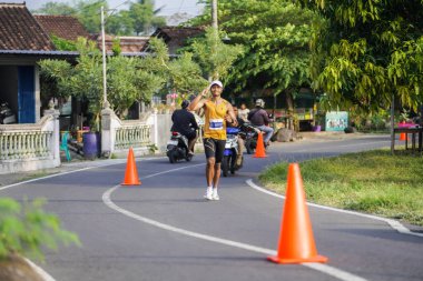 Jogja Maratonu 42K 'nın katılımcıları veya koşucuları, Prambanan tapınak köyünün etrafından güzel bir yoldan geçiyorlar. : Yogyakarta, Endonezya - 18 Haziran 2023