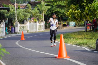 Jogja Maratonu 42K 'nın katılımcıları veya koşucuları, Prambanan tapınak köyünün etrafından güzel bir yoldan geçiyorlar. : Yogyakarta, Endonezya - 18 Haziran 2023