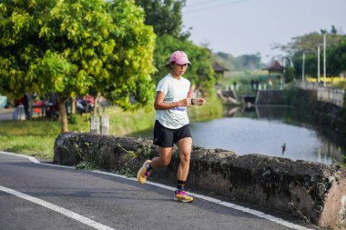 Jogja Maratonu 42K 'nın katılımcıları veya koşucuları, Prambanan tapınak köyünün etrafından güzel bir yoldan geçiyorlar. : Yogyakarta, Endonezya - 18 Haziran 2023