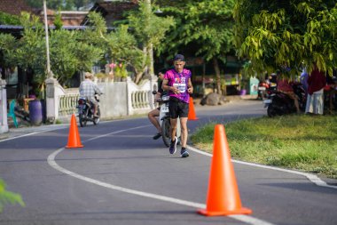 Jogja Maratonu 42K 'nın katılımcıları veya koşucuları, Prambanan tapınak köyünün etrafından güzel bir yoldan geçiyorlar. : Yogyakarta, Endonezya - 18 Haziran 2023