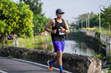 Jogja Maratonu 42K 'nın katılımcıları veya koşucuları, Prambanan tapınak köyünün etrafından güzel bir yoldan geçiyorlar. : Yogyakarta, Endonezya - 18 Haziran 2023