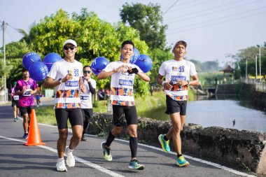 Jogja Maratonu 42K 'nın katılımcıları veya koşucuları, Prambanan tapınak köyünün etrafından güzel bir yoldan geçiyorlar. : Yogyakarta, Endonezya - 18 Haziran 2023